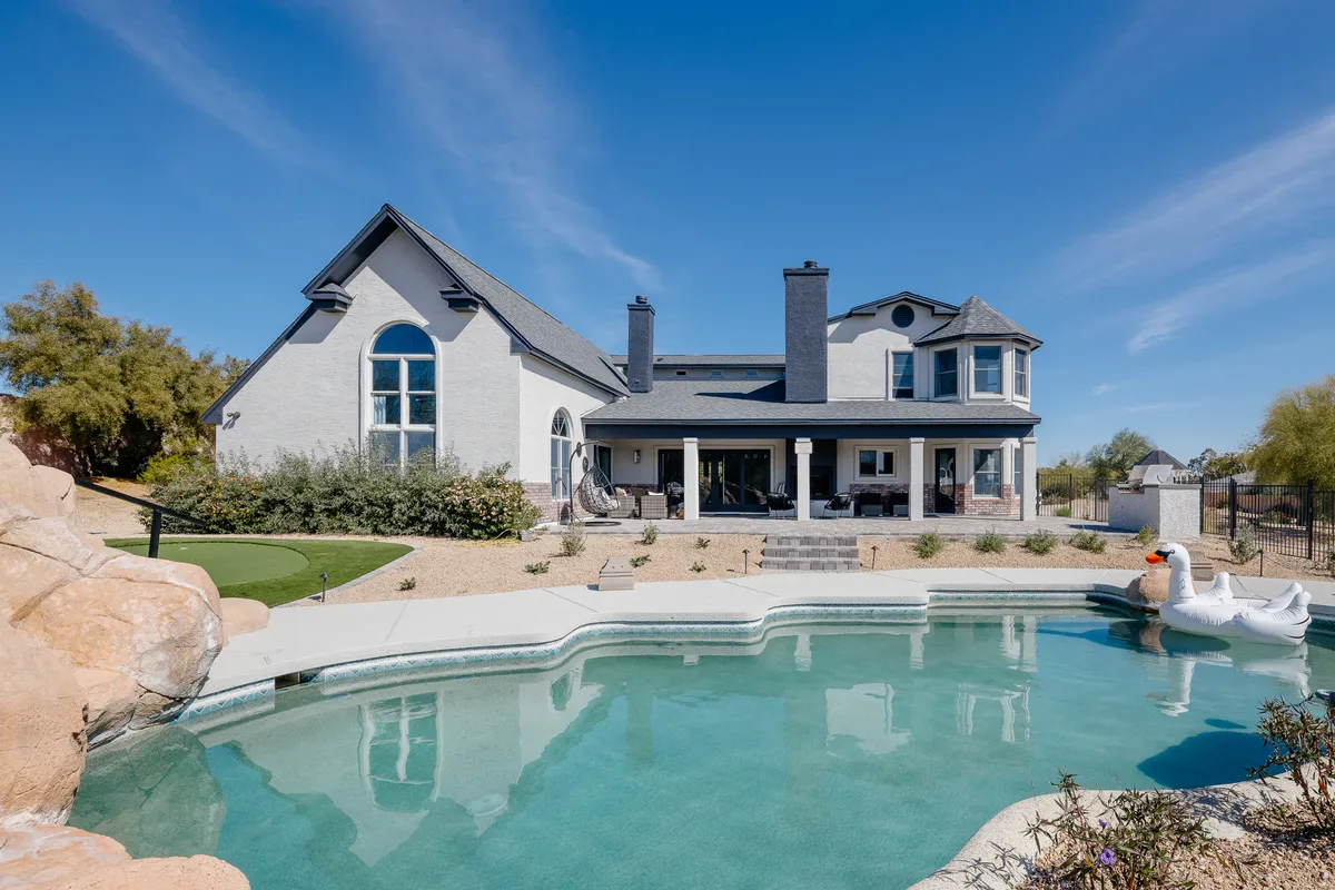 This exterior image showcases a sparkling swimming pool with a decorative swan float, a spacious backyard patio, and the home’s facade in the background. The scene is inviting and playful, evoking a sense of relaxation and fun for families or groups enjoying the outdoors together.