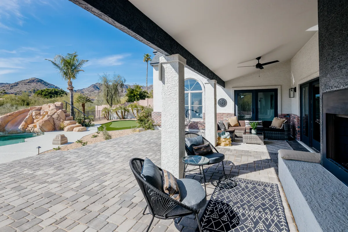 An inviting outdoor seating area beside a large swimming pool with a dramatic mountain backdrop and landscaped gardens. The space is set for relaxation or entertaining, with plush seating that encourages gatherings and stargazing.