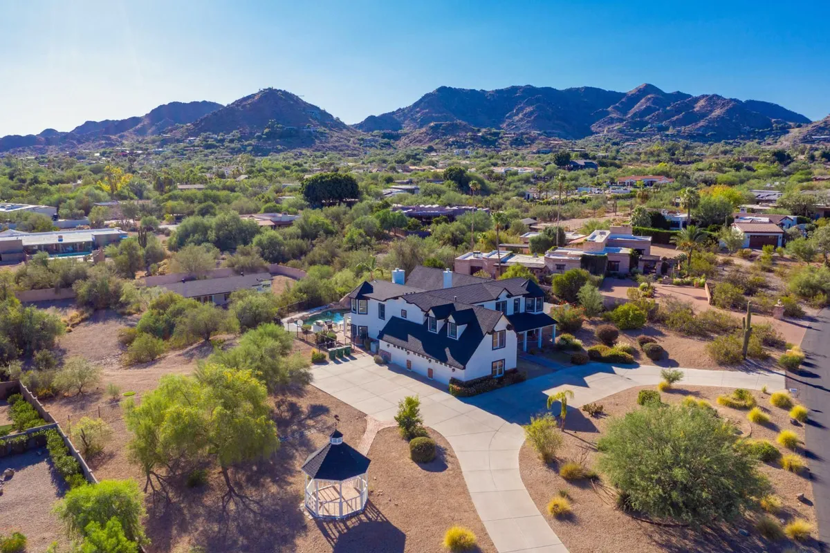 A spacious luxury mansion set against a backdrop of surrounding mountains, complete with a gazebo and a welcoming driveway. The home’s expansive outdoor spaces suggest opportunities for relaxation, socializing, and exclusive gatherings.